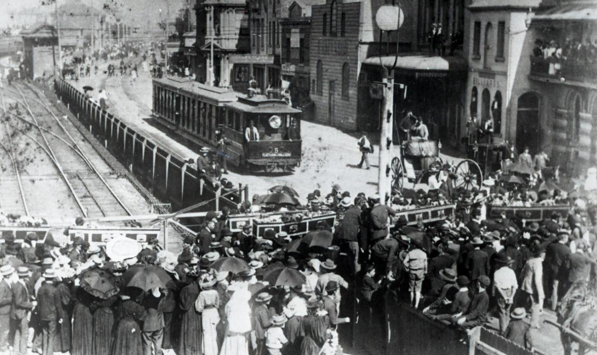 Funeral procession 1896 for 11 miner workers with train in background and people in foreground