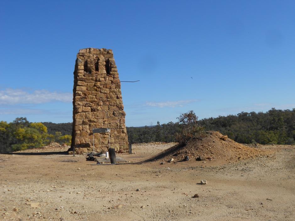 Ruins of stone chimney stack in red desert with blue sky.